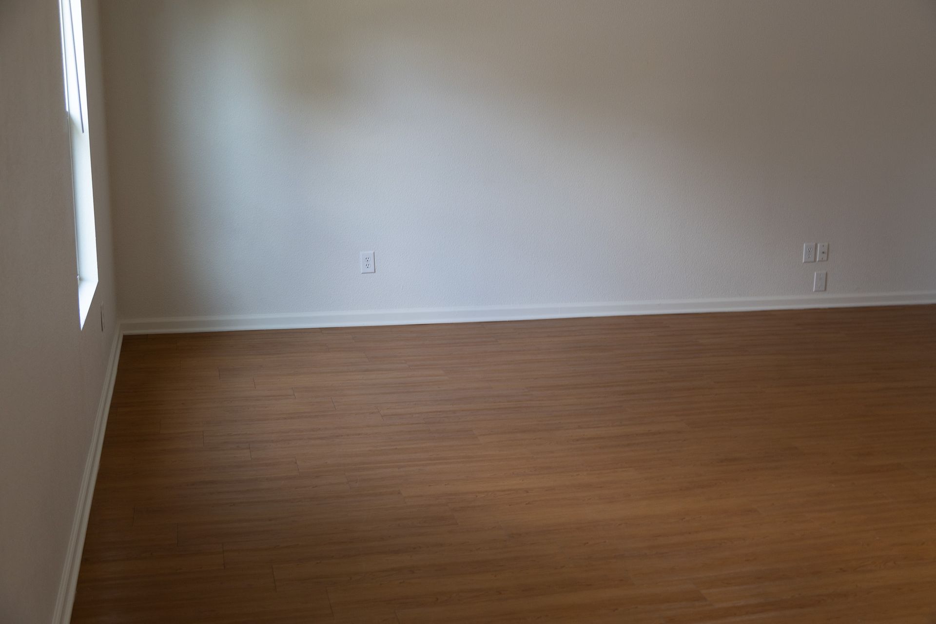 An empty room with a wooden floor and white walls