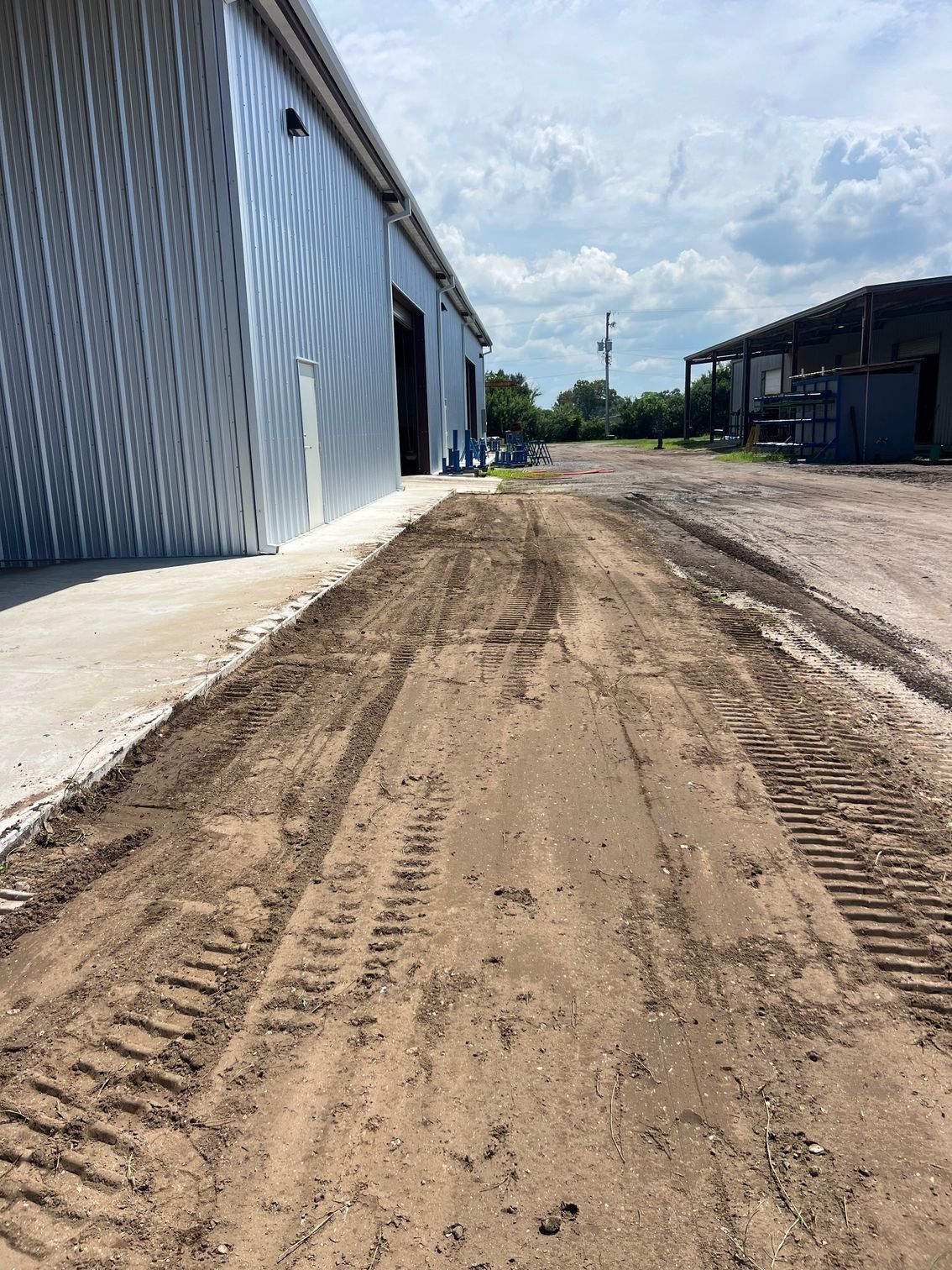 A hillside with areas of exposed soil, tan and green erosion control, and trees.
