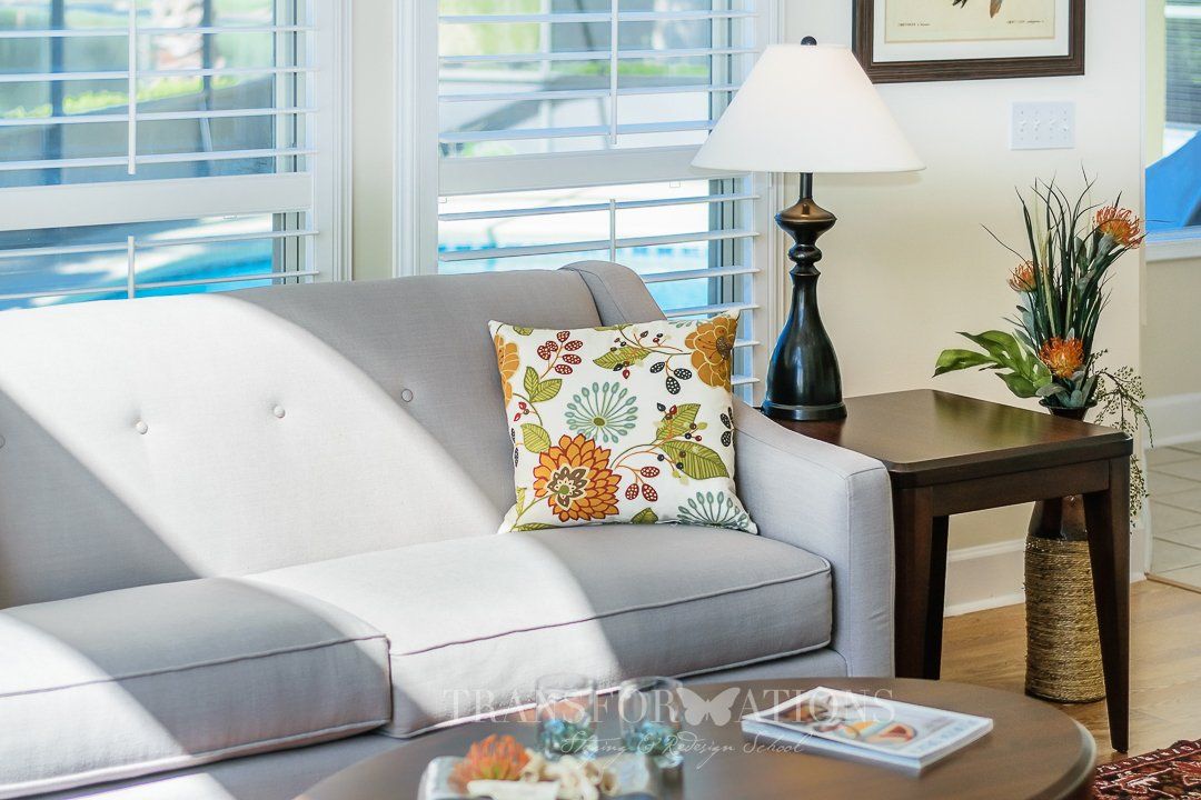 A living room with a couch , chair , table and lamp.