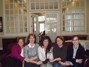 A group of women are posing for a picture while sitting on a couch.