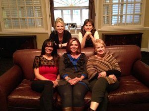 A group of women are posing for a picture while sitting on a couch