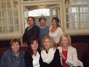 A group of women are posing for a picture while sitting on a couch.