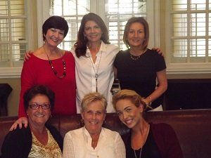 A group of women are posing for a picture while sitting on a couch.