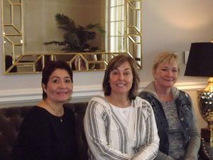 Three women are posing for a picture while sitting on a couch.