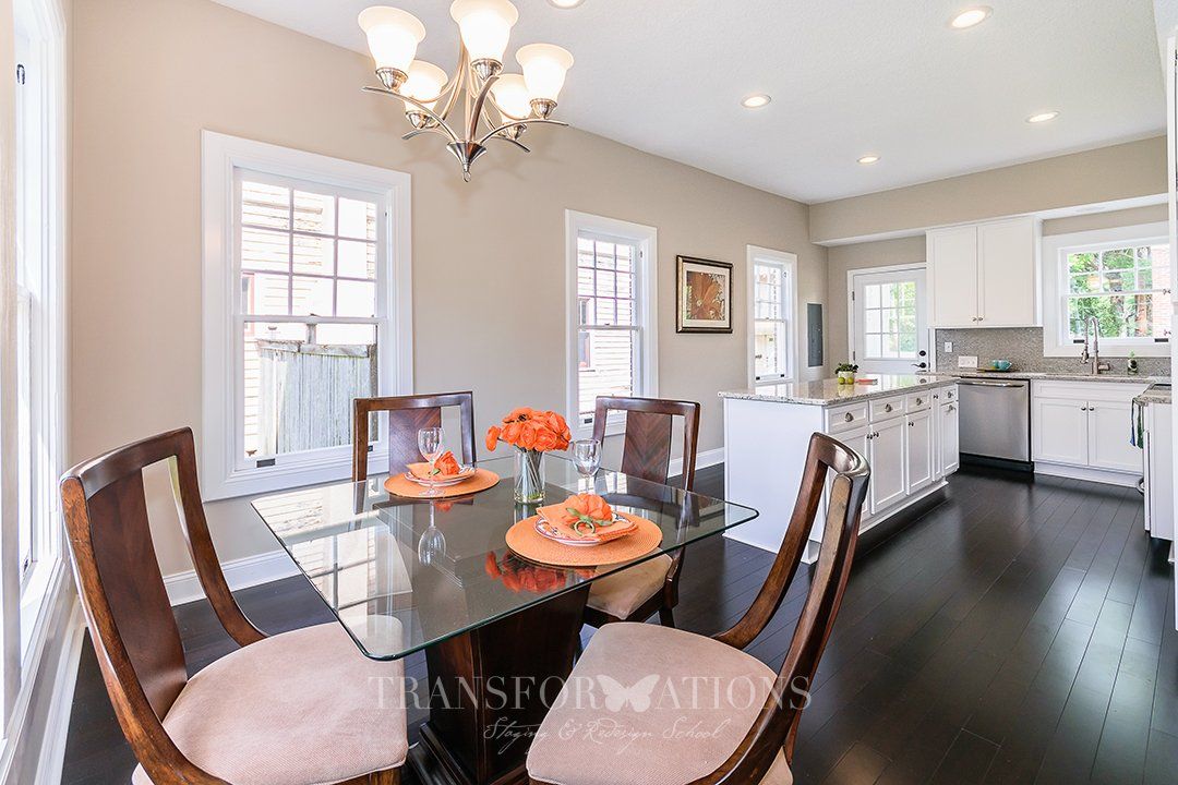 A dining room with a glass table and chairs and a kitchen.
