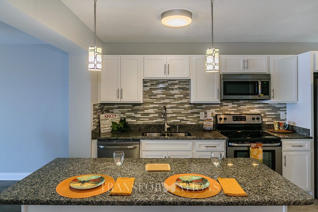 A kitchen with granite counter tops , stainless steel appliances , and white cabinets.