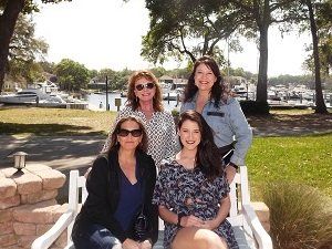 Four women are posing for a picture while sitting on a bench