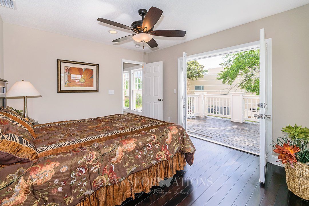 A bedroom with two beds , a ceiling fan , and a balcony.