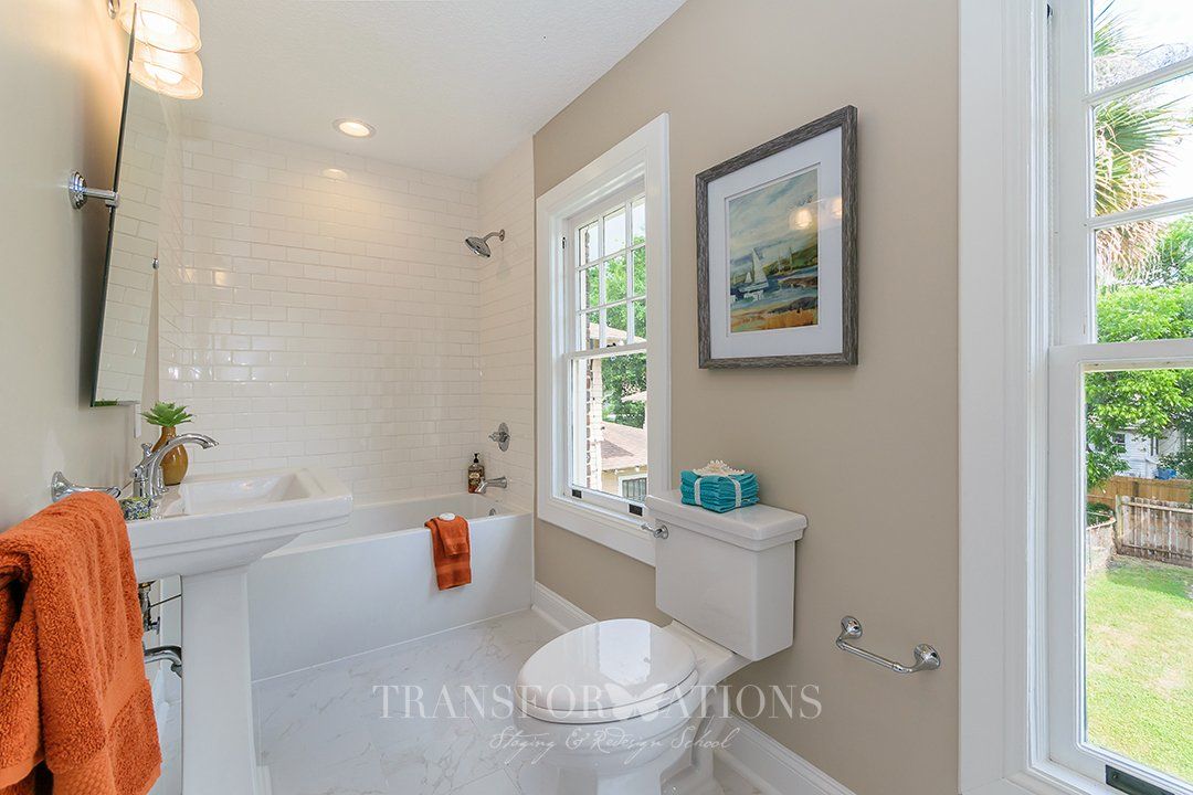 A bathroom with a tub , toilet , sink and window.