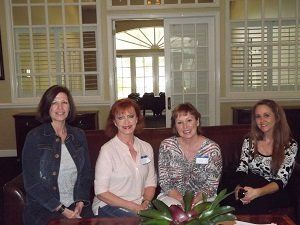 Four women are posing for a picture in a living room
