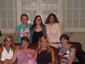 A group of women are posing for a picture while sitting on a couch.