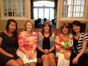 A group of women are posing for a picture while sitting on a couch.
