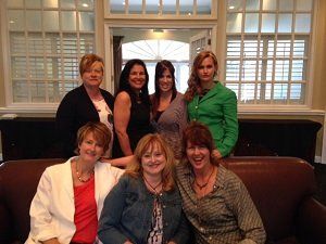 A group of women are posing for a picture while sitting on a couch.