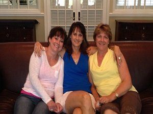 Three women are posing for a picture while sitting on a couch.