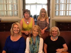 A group of women are posing for a picture while sitting on a couch.