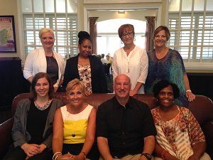 A group of people are posing for a picture while sitting on a couch.