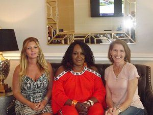 Three women are posing for a picture while sitting on a couch.