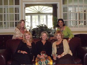 A group of women are posing for a picture while sitting on a couch.