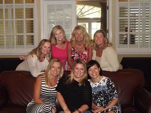 A group of women are posing for a picture while sitting on a couch.