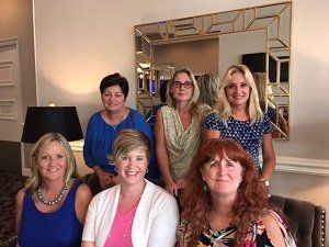 A group of women are posing for a picture in front of a mirror.