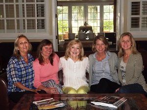 A group of women are posing for a picture while sitting around a table.
