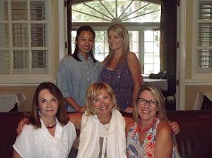 A group of women are posing for a picture while sitting on a couch.