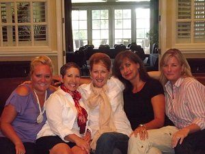 A group of women are posing for a picture while sitting on a couch.