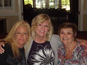 Three women are posing for a picture together and smiling for the camera.
