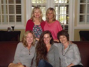 A group of women are posing for a picture while sitting on a couch.