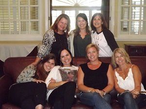 A group of women are posing for a picture while sitting on a couch