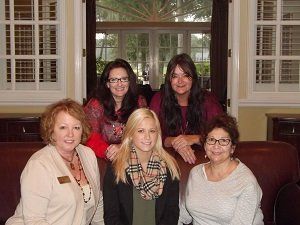 A group of women sitting on a couch posing for a picture