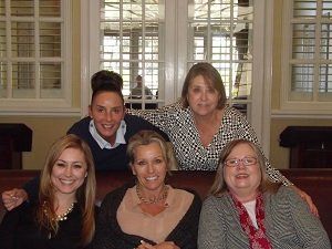 A group of women are posing for a picture while sitting on a couch.