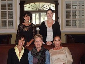 A group of women are posing for a picture while sitting on a couch