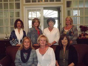 A group of women are posing for a picture while sitting on a couch.