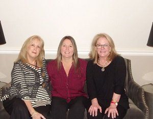 Three women are posing for a picture while sitting on a couch