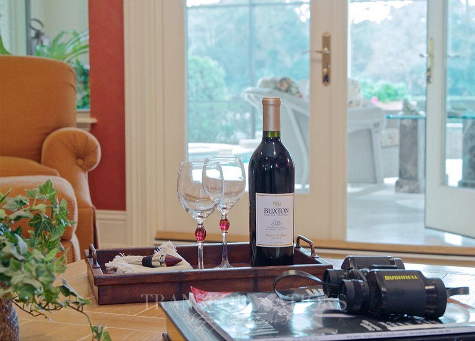 A bottle of wine sits on a tray next to two wine glasses
