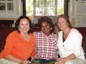 Three women are posing for a picture in front of a club sign