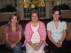 Three women are posing for a picture while sitting on a couch