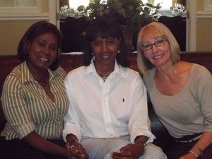 Three women are posing for a picture while sitting on a couch