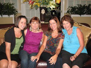 Four women are posing for a picture while sitting on a couch