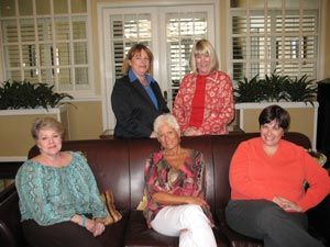 Four women are sitting on a couch in a living room