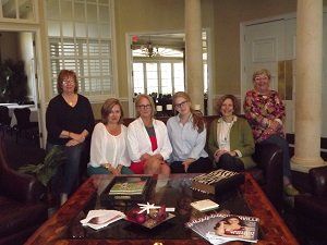A group of women are sitting around a table in a living room.