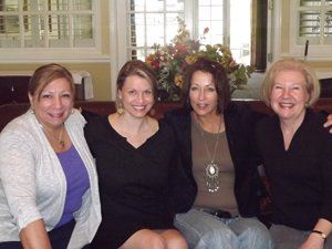Four women are posing for a picture while sitting on a couch
