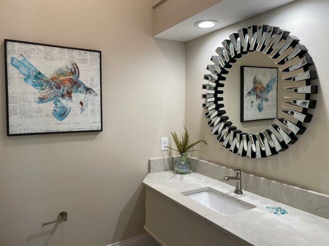 A bathroom with a sink a mirror and a painting on the wall