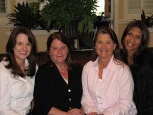 Four women are posing for a picture together and smiling