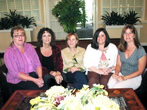 A group of women are sitting around a table with flowers