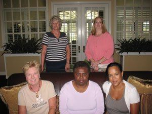 Four women are posing for a picture in a living room