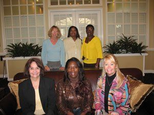 A group of women are posing for a picture while sitting on a couch.