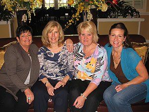 Four women are posing for a picture while sitting on a couch