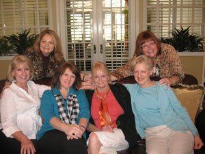 A group of women are posing for a picture while sitting on a couch.